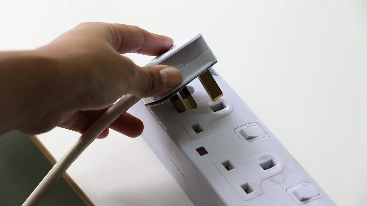 UK three-pin plug going into a socket (stock photo)